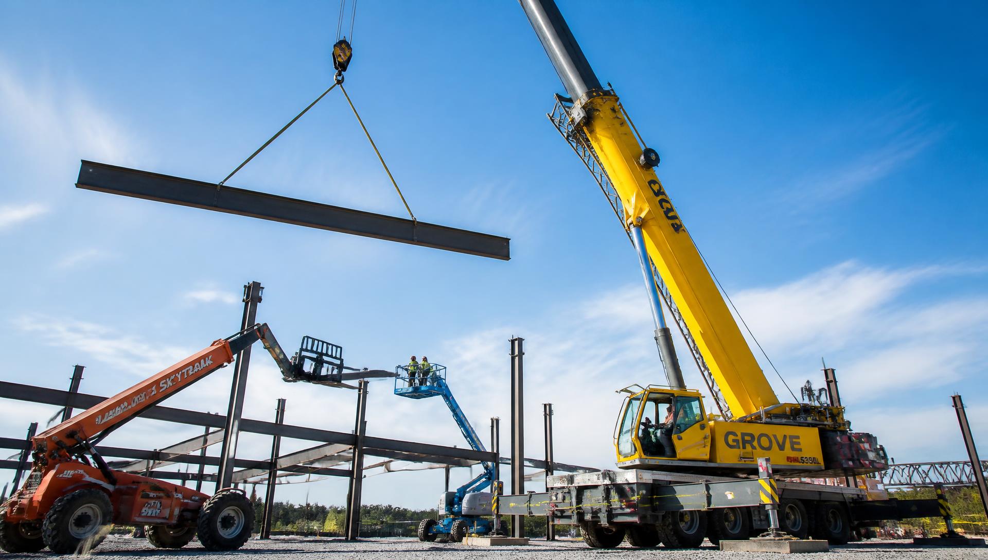 Grue mobile levant une poutre métallique avec nacelle et chariot télescopique